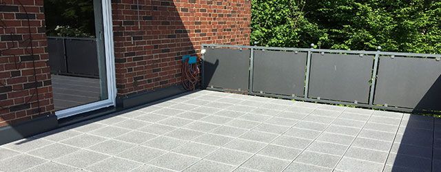 Sanierter Balkon mit schwarzem Geländer und grauen Fliesen