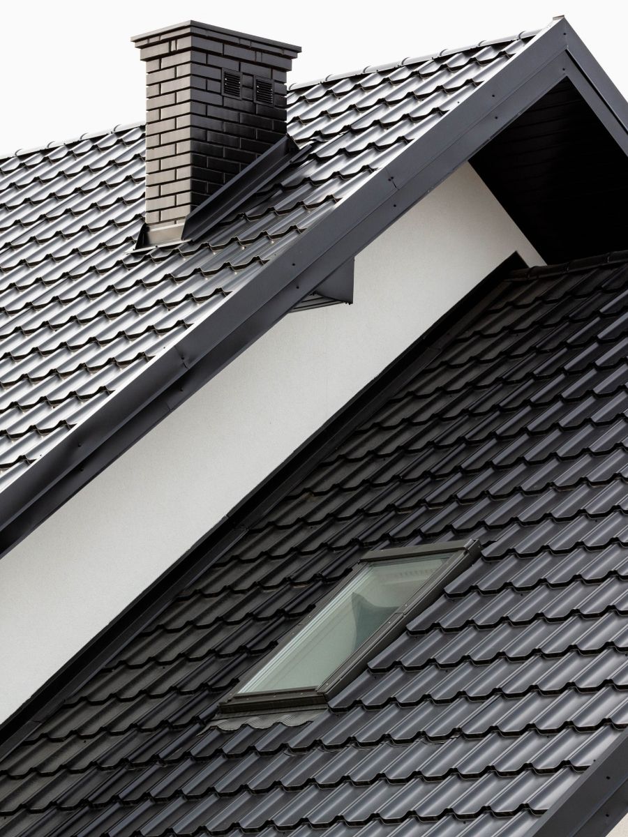 Saniertes, schwarzes Dach mit Kamin und Dachfenster